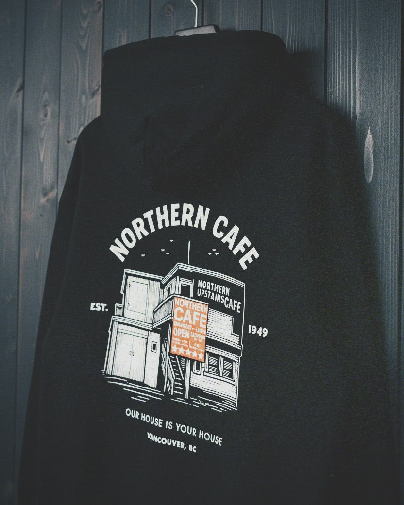 Black hoodie with Northern Cafe graphic design on a wooden background