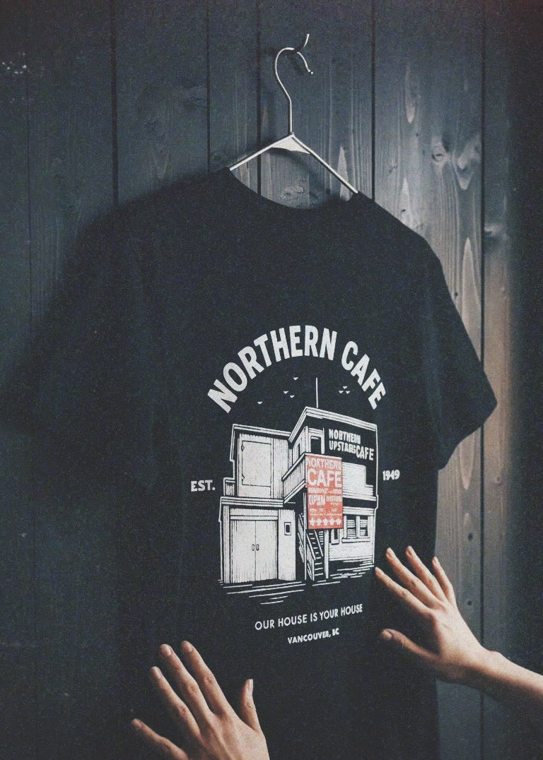 Black t-shirt with 'Northern Cafe' graphic design on a wooden background