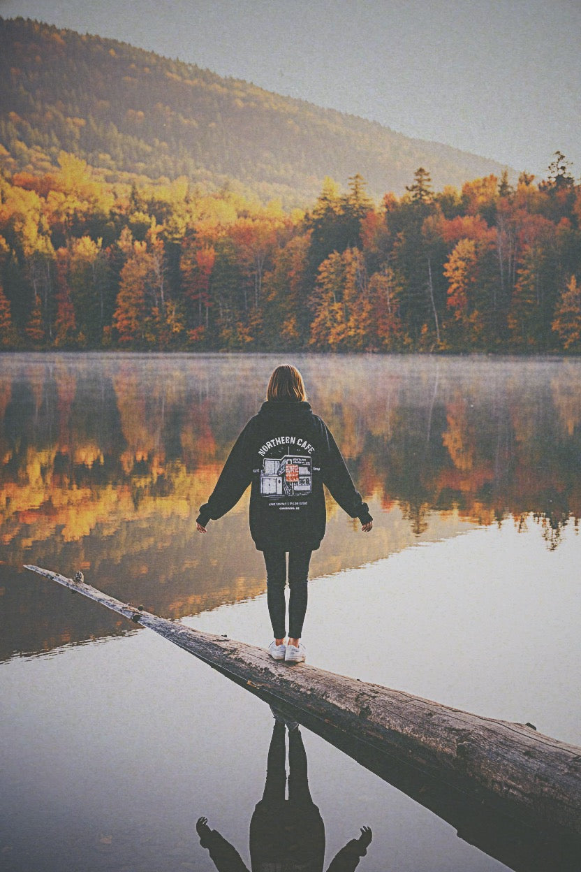 Person walking on a log over a lake with autumn foliage in the background