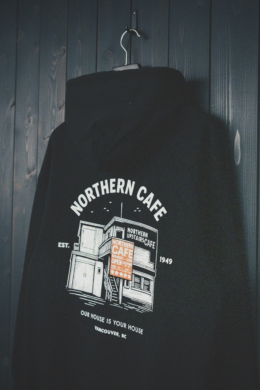 Black hoodie with Northern Cafe graphic design on a wooden background