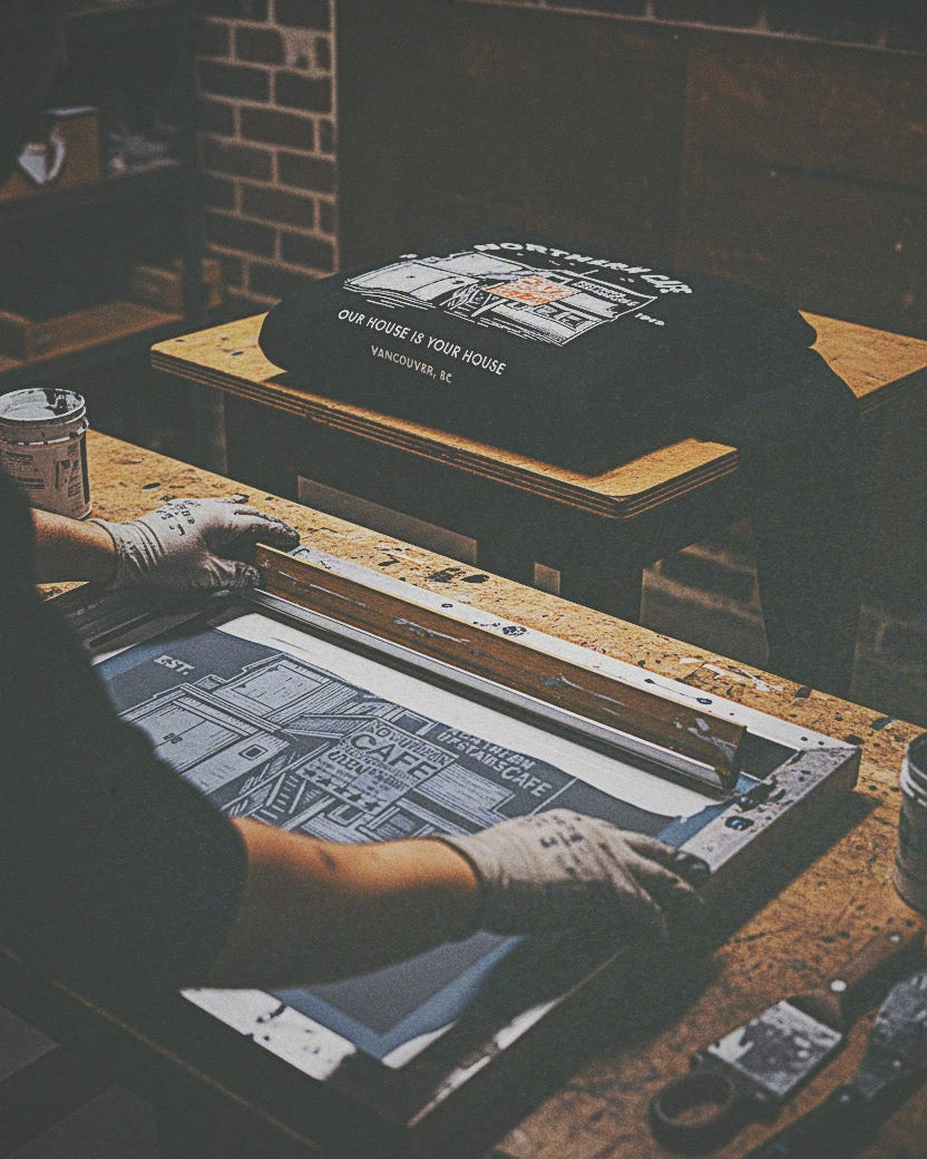 Person screen printing on a t-shirt with a dark background